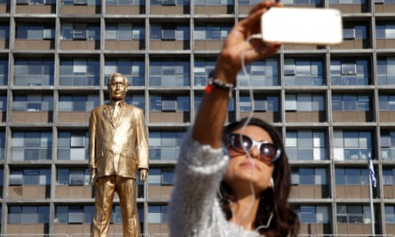 woman takes a selfie with the golden Netanyahu statue