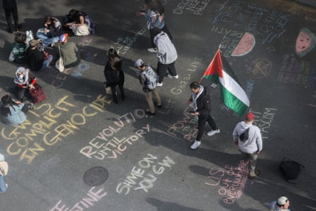 students hold palestinian flags and write messages in chal, saying ‘GW is complicit in genocide’ and other slogans