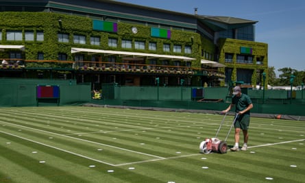 Ground staff mark out lines on a court at the All England Lawn Tennis Club, Wimbledon.