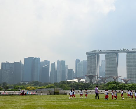 People on grass with Singapore skyline behind.