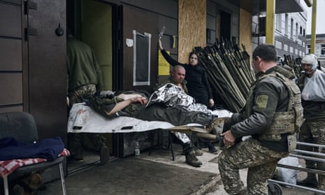 Ukrainian soldiers carry a wounded soldier into a hospital in Bakhmut