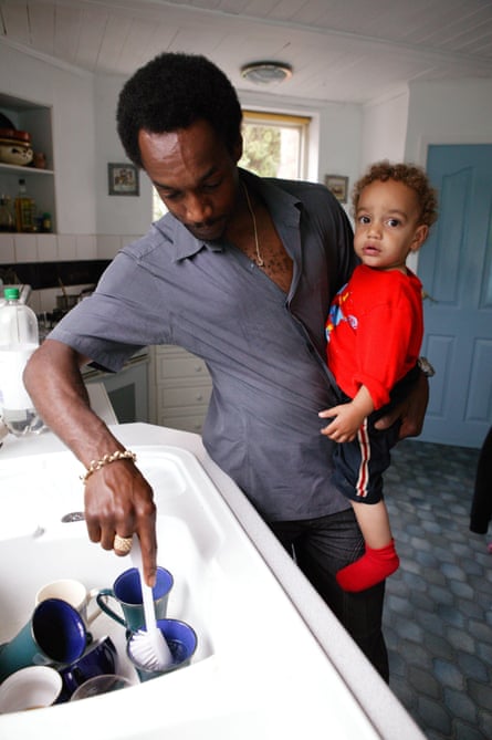 Man washing dishes while holding his young son