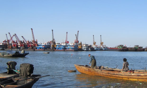 Fishers on Lake Poyang look out at industrial sand dredging boats.