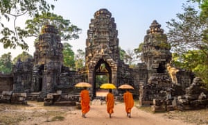 Buddhist monks walking inside Angkor Wat templeThree buddhist monks with umbrellas, walking inside Angkor Wat temple. Siem Reap, Cambodia