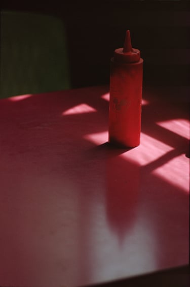 A red ketchup bottle on a red table