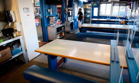 An employee stands by empty bench tables inside at “Eat At Joe’s”.