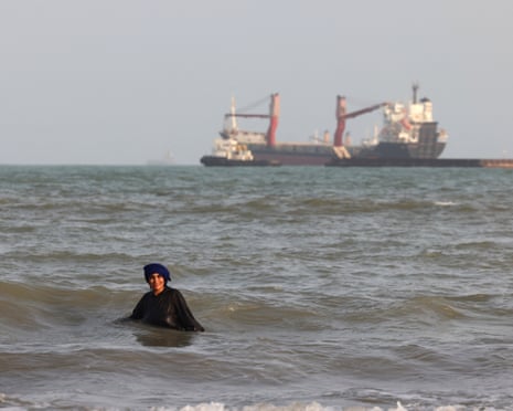 An Iranian women enjoys a dip in the sea as vessels are seen in the Strait of Hormuz off the port city of Bandar Abbas, in southern Iran on 10 August.