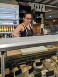 Sahra Baadache, 27, a cheesemonger in the Marché St Quentin food market in Paris, France, behind her cheese counter.