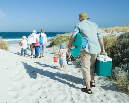 A family walking through dunes to a beach.