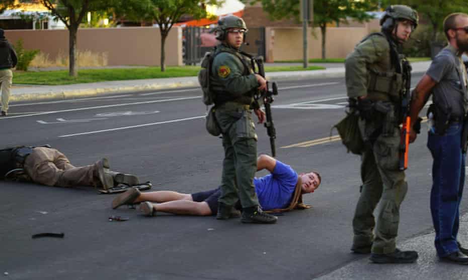 Steven Baca, center, taken into custody after he shot and wounded a man as the crowd tried to take down statue in Albuquerque, on 15 June.