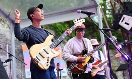 Benson (L) and Yun Jin (R) of The Chairs on stage at a festival holding guitars and playing