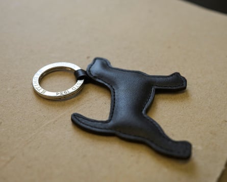 A black leather dog-shaped keyring charm from Ettinger lies beside a silver keyring