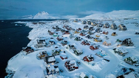 Birdseye shot of dozens of homes in the snow, next to the coast