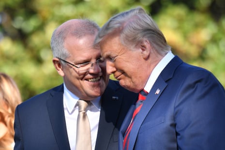 A man with grey hair and glasses speaks to a man with light hair.