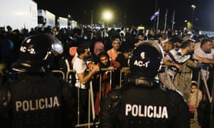 Refugees stand behind a fence blocking the crossing from Croatia to Slovenia at the border checkpoint in Obretzje.