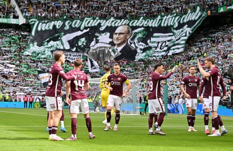 Hearts players gee each other up in front of a Celtic tifo just before kick off.