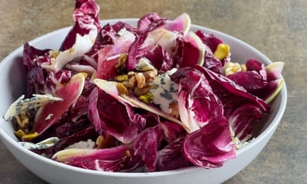 Bowl of radicchio salad with nuts and blue cheese on brown, weathered background