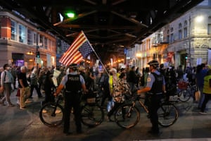 Protesters walk past two police officers holding bicycles