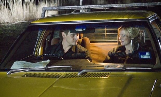 A man and a woman look at each other tenderly in the dimly lit cabin of a ute (light pickup truck)