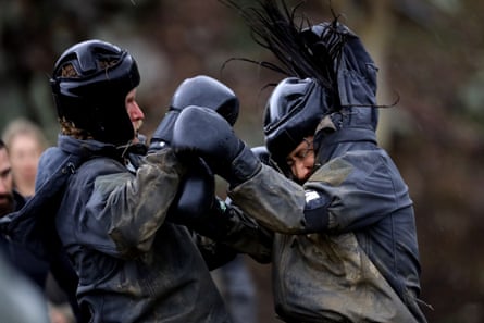 two people boxing in muddy black gear