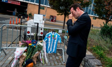 A local resident reacts after placing an Argentinian football jersey at a makeshift memorial for the terror attack victims along a bike path in New York.