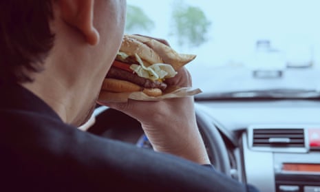 Man eating a burger while driving