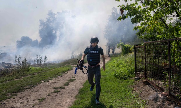 A journalist runs as smoke rises behind after a bombardment in Bakhmut, eastern Ukraine, on Sunday.
