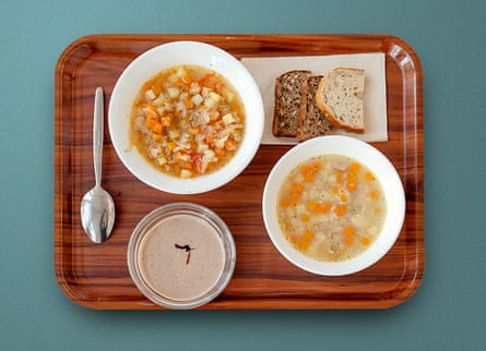 Two bowls of soup on a tray, with a plate of different breads