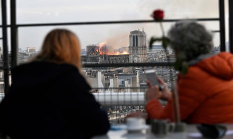 People look at the flames burning the roof of the Notre-Dame Cathedral in Paris.