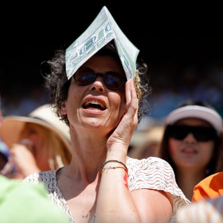 A spectator on No 1 Court uses a guide to shelter from the sun as she watches Jannik Sinner.
