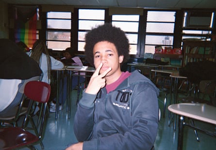 An image of a boy wearing a grey hoodie making a peace sign with his fingers.