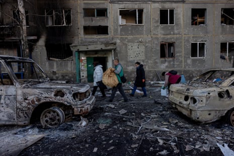 People carry their belongings as they leave their damaged residential building after a strike in Dobropillia, Donetsk region.