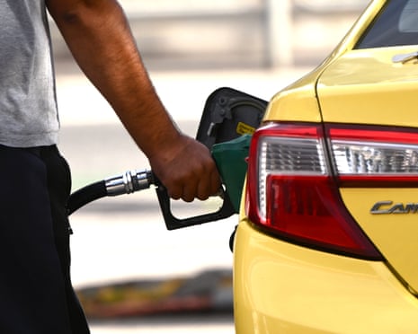 A man's hand filling up a yellow car with fuel 