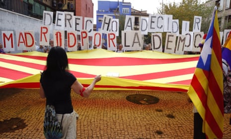People unfurl a Catalan flag and hold posters reading ‘Right to Decide. Madrid for Democracy’.