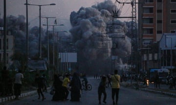 Palestinians watch smoke billowing following an Israeli airstrike in Deir al-Balah on Thursday.