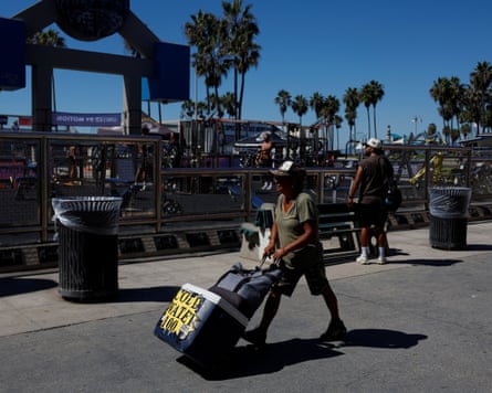 A vendor walks with a cooler during high temperatures at Venice Beach.