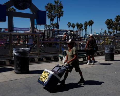 A vendor pulls a wheeled cooler marked Cold Water along Venice Beach boardwalk