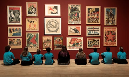 Schoolchildren in front of a wall of Soviet Union propaganda posters at the Red Star Over Russia exhibition.