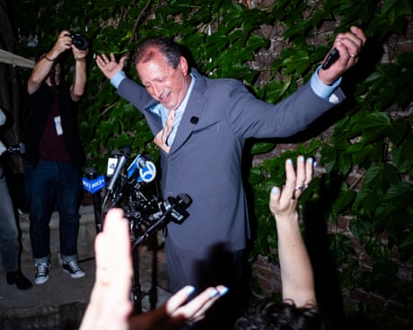 a man raises his arms as people cheer