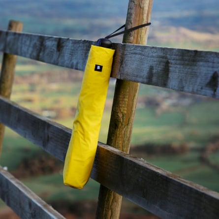 Folded-up compact umbrella in its sleeve hanging from a fence post