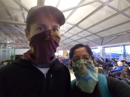 Charlie and Sashi wearing scarfs to cover their mouths, standing at the airport