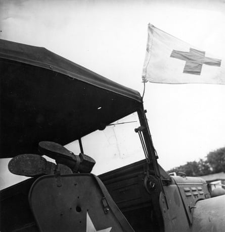 A black and white image shows a pair of boots sticking out the side of a military ambulance with