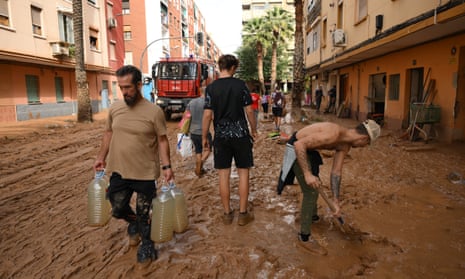 People carry water and shovel mud after flooding hit large parts of the country on October 31, 2024 in the Paiporta municipality of Valencia, Spain. By Thursday, Spanish authorities confirmed that at least 95 people had died, mostly in the Valencia region, amid the flooding that swept eastern and southern parts of the country starting on Tuesday. The intense rainfall event is known as a "cold drop" or DANA weather system