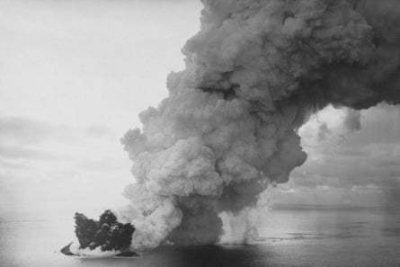 A black-and-white photo of a huge plume of smoke billowing up as explosions appear from beneath the sea