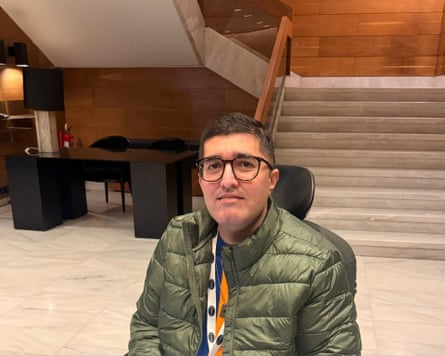 Hasan Adeel sitting down, with a desk and stairs visible behind him