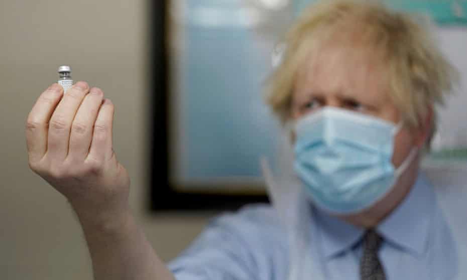 Boris Johnson holds a bottle of the Pfizer BioNTech vaccine as he visits a Covid-19 vaccination centre in Batley