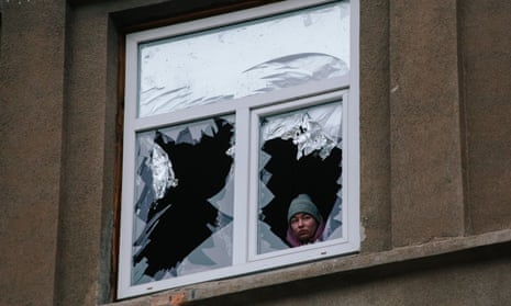 A woman looking out of a window that has been broken by an explosion, in Kharkiv, Ukraine, on 8 December, 2023.
