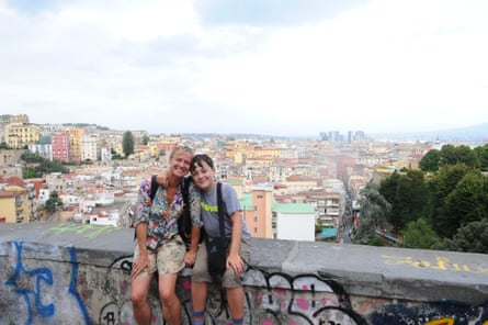 A woman and boy sitting on a wall above a city