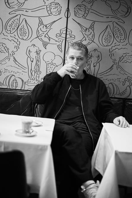 Black and white image of Pav drinking a coffee in a fashionable looking cafe