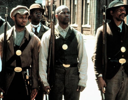 Three men of colour standing to attention. They are wearing heavy suits with big gold adornments on them